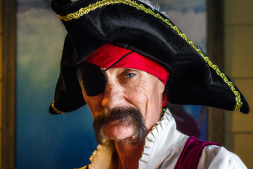 pirate with an eye patch and one piercing eye looks intesly at the camera he has a tripoint hat and 