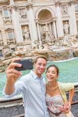 Wall Mural - Rome couple at Trevi Fountain Italy vacation. Happy young travel tourists traveling in Europe taking photo with phone camera. Man and Asian woman happy together.