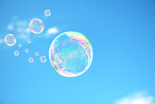 The Beautiful Soap Bubbles With Reflection And Glare Are In A Blue Sky.