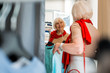 © zinkevych - Weekend shopping. Waist up of adorable elderly woman choosing summer dress in clothing store while expressing delightful emotions on her face