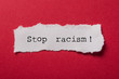 closeup of white torn paper on red paper background - Stop racism !