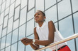 © LIGHTFIELD STUDIOS - low angle view of stylish attractive african american businesswoman leaning on railing near business center