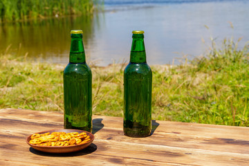 Two bottles of beer on wooden table near a river