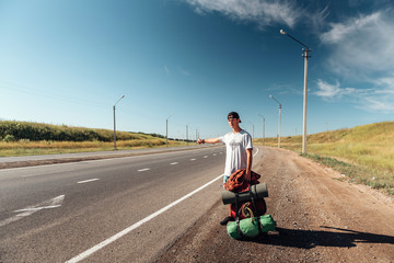 Travel man hitchhiking. Backpacker on road