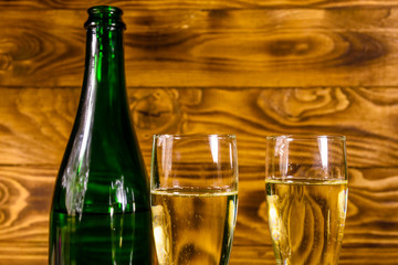 Bottle of champagne and two wineglasses on wooden table