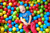 Fototapeta Miasta - Laughing child in a game pool with colorful balls