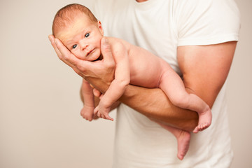 father holding new born baby on his arm