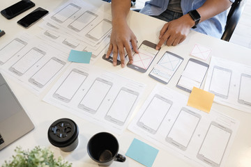 ux designer sketching smartphone layout for business application prototype.