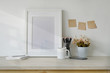 Mockup workspace table with white poster frame, coffee mug, notebook and supplies.