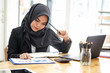 © bongkarn - Attractive female Arabic corporate worker working on laptop computer on desk