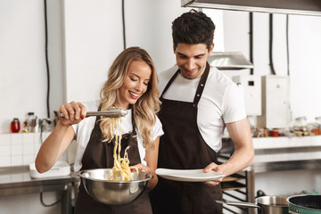 Smiling excited young friends loving couple chefs on the kitchen cooking.