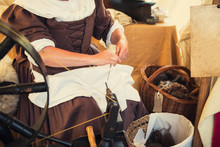 Cropped Image Of Weaver In Middle Agesl Clothes Make Yarn On Spinning Wheel. Medieval Crafts, Occupation. The Concept Of Historical Development Of Weaving In England. Selective Focus. Copy Space.