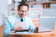 © Viacheslav Yakobchuk - Let me count. Happy mature male keeping smile on his face while sitting at his workplace in cafe