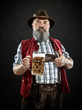Germany, Bavaria, Upper Bavaria. The smiling man with beer dressed in in traditional Austrian or Bavarian costume in hat holding mug of beer at studio