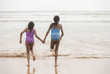 © Paul - Rear view of two mixed-race sisters running into the water playing and laughing having fun on the beach on a bright tropical summer holiday