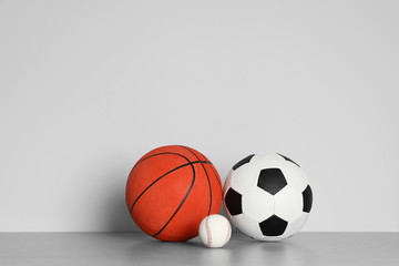 Different sport balls on table against color background. Space for text