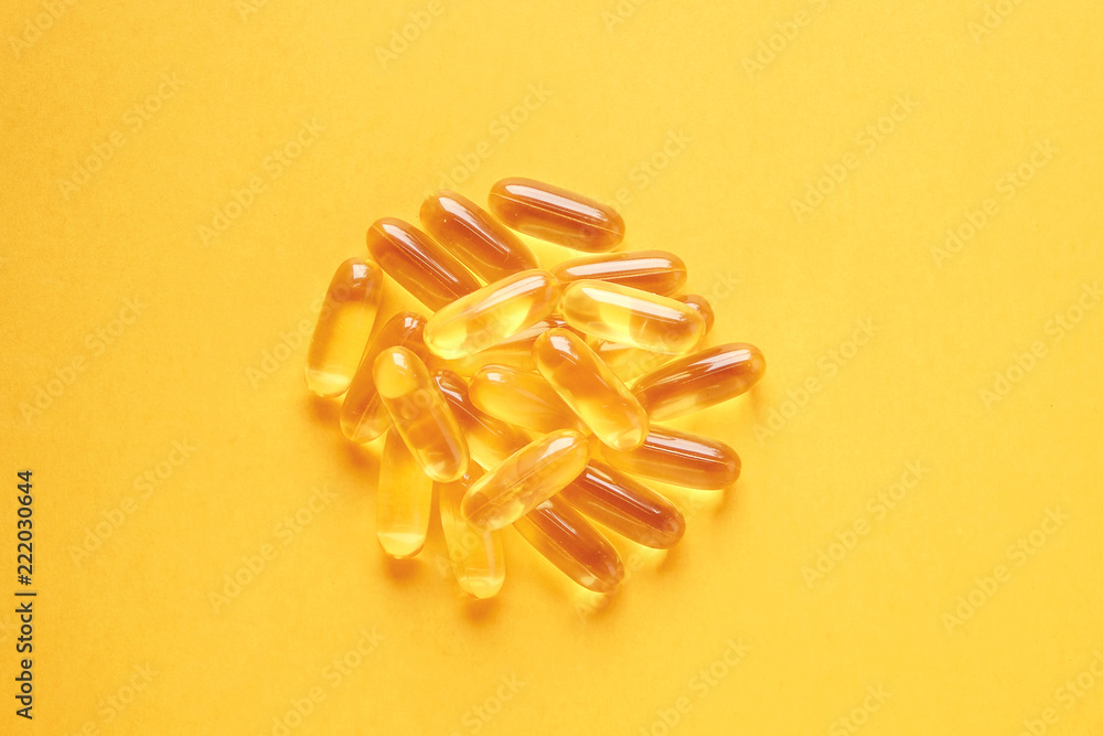 Obraz na płótnie Bunch of omega 3 fish liver oil capsules forming circle shaped pattern. Close up of big golden pills texture. Healthy every day nutritional supplement. Top view flat lay, copy space, yellow background w salonie