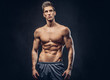 © Fxquadro - Handsome shirtless ectomorph bodybuilder with stylish hair posing on a dark background.