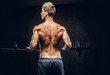 © Fxquadro - Back view of shirtless man with stylish hair and muscular ectomorph doing the exercises with the barbell.