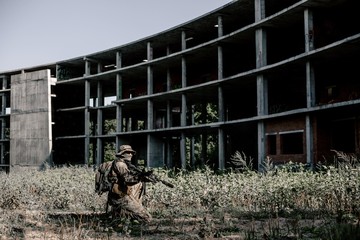 Military soldier in camouflage in the war took a fighting position to shoot at the destroyed building