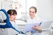 © pantovich - Dentist in white uniform shows the results of the examination to the client in the dental clinic