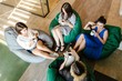 © pantovich - Four girls drinking coffee on a break sitting on a bean bag in the office, top view