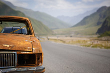 Old Rusty Burned Car On The Roadside Of Georgia, Surrounded By Mountains And Beauty