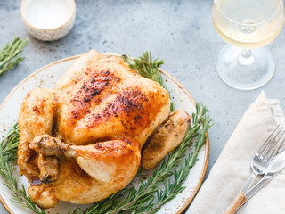 Wall Mural - Whole grill chicken with caramelized skin and fresh rosemary on a dinner table.