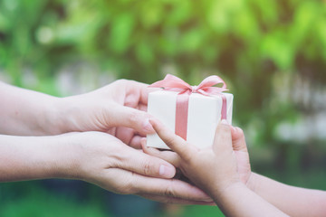 Holidays, present, christmas, Valentines day childhood and happiness concept - close up of  little girl and mother hands with gift box green background. selective focus.soft focus