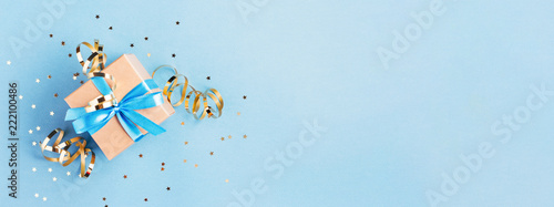 Christmas gift box with golden decorations and sparkles on blue bacground. Gi...