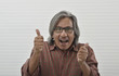 © grapestock - Portrait of happy asian senior businessman in red casual shirt making thumbs up over white wall, Business confident and success concept