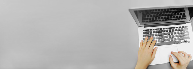 website banner of top view laptop and female hands with copyspace in grey color background. concept 