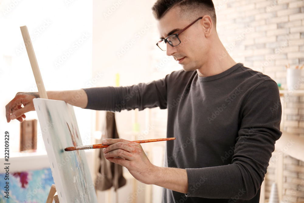 Male artist painting on canvas in workshop