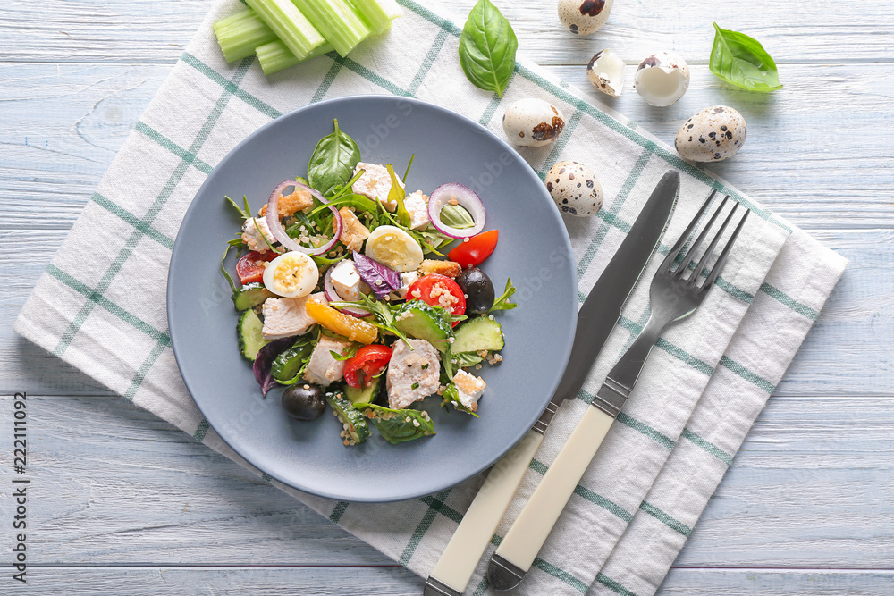 Plate with tasty chicken salad on wooden table