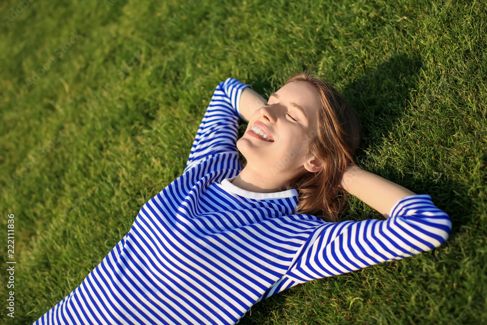 Young woman lying on green grass outdoors
