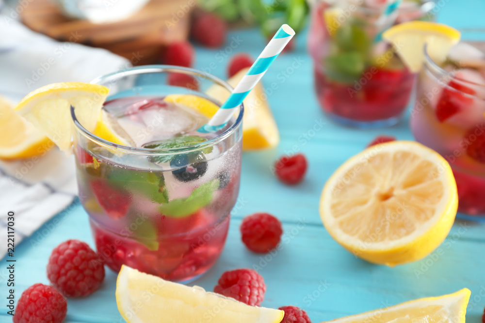 Glass of fresh raspberry mojito on wooden table