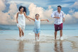 © ID_Anuphon - Happy asian family - father, mother, kid hold hands and run together with fun along daylight sea beach. Travel, active lifestyle, parents with children on tropical summer vacations.