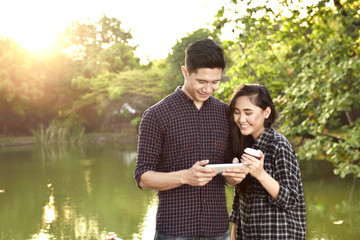 Wall Mural - Attractive asian couple with tablet on the park