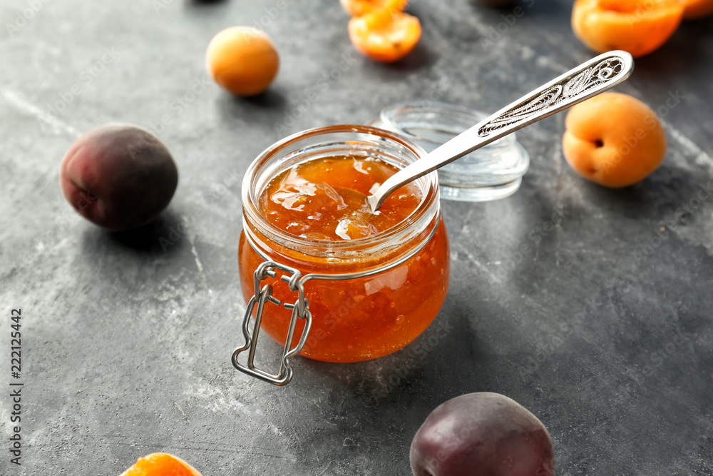Jar with delicious apricot jam and fresh fruit on grunge table