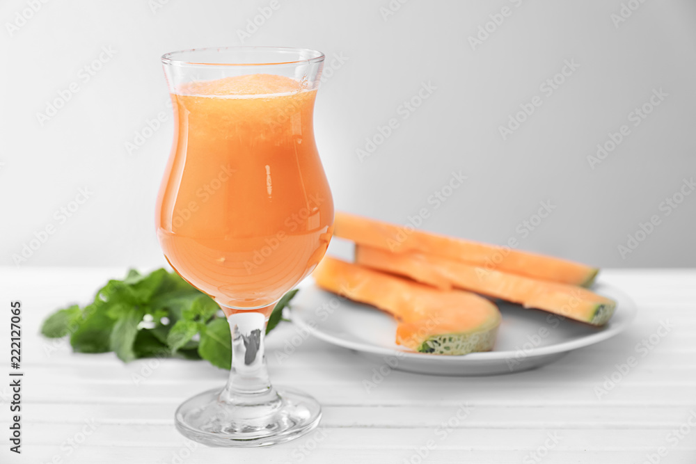 Glass with delicious melon smoothie on white wooden table