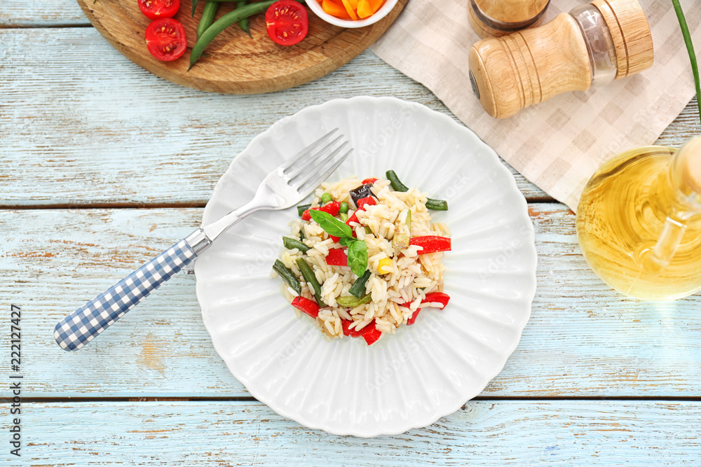 Plate with tasty boiled rice and vegetables on wooden table