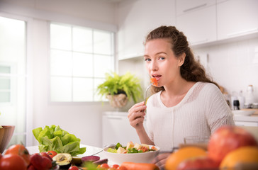 Healthy young woman eating salad in the kitchen