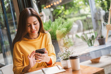 Young Asian Beautiful Woman Using Smart Phone For Business, Online Shopping, Transfer Money, Financial, Internet Banking. In Coffee Shop Cafe Over Blurred Background.
