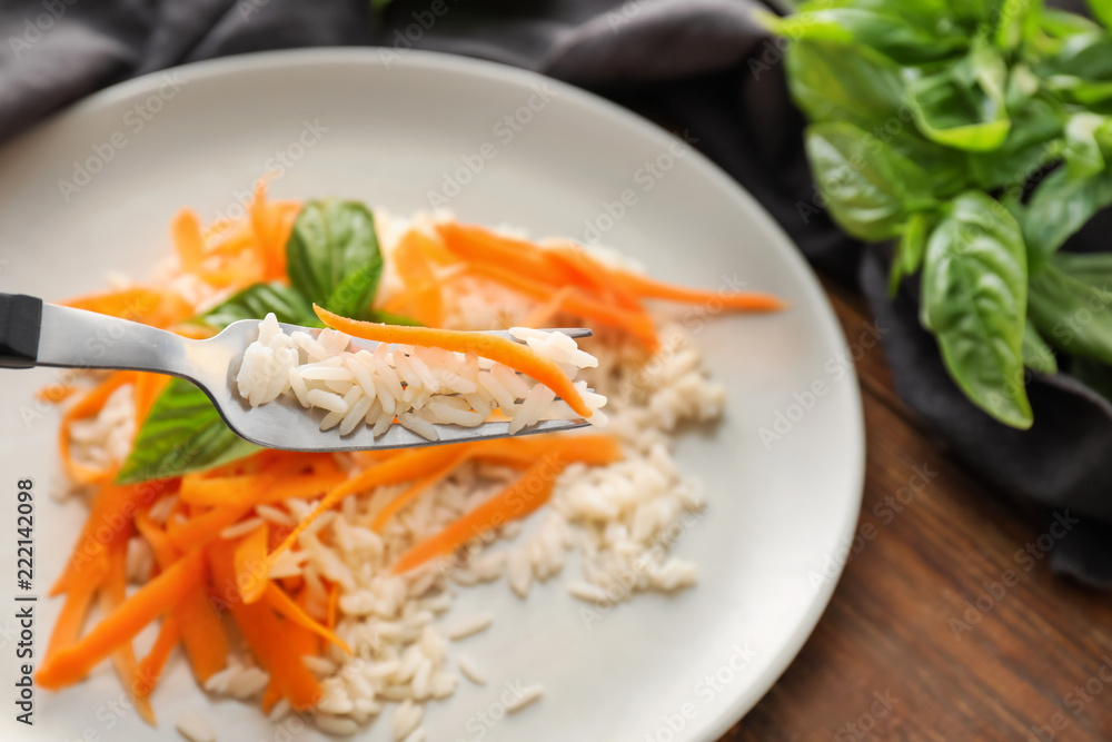 Eating of boiled rice with carrot, closeup