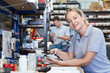 © highwaystarz - Portrait Of Female Engineer In Factory Measuring Component At Work Bench Using Micrometer