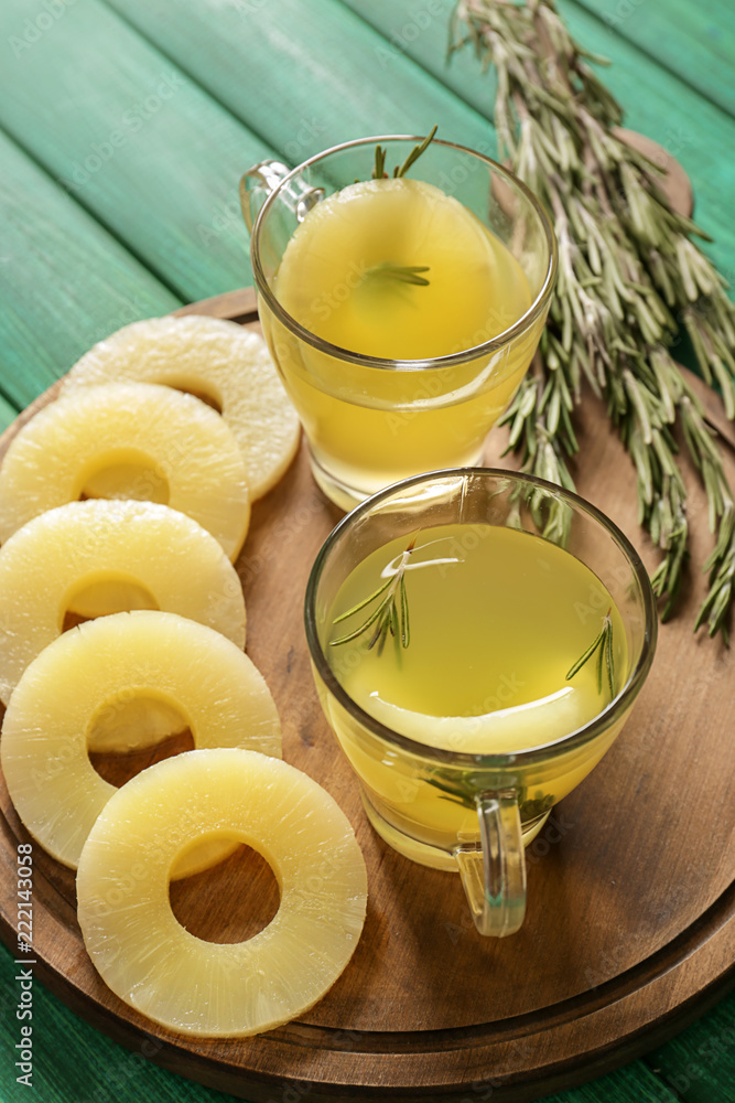 Cups with tasty drink and sliced pineapple on wooden board