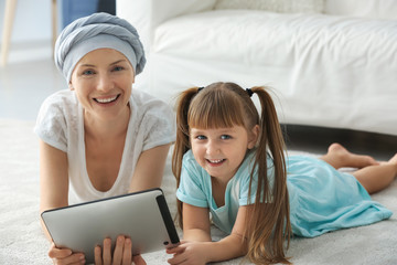 Sticker - Little girl and her mother after chemotherapy using tablet PC at home