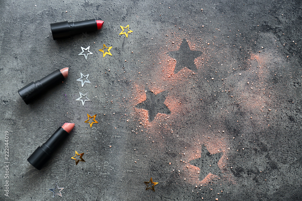 Composition with color lipsticks, stars and powder on grey background