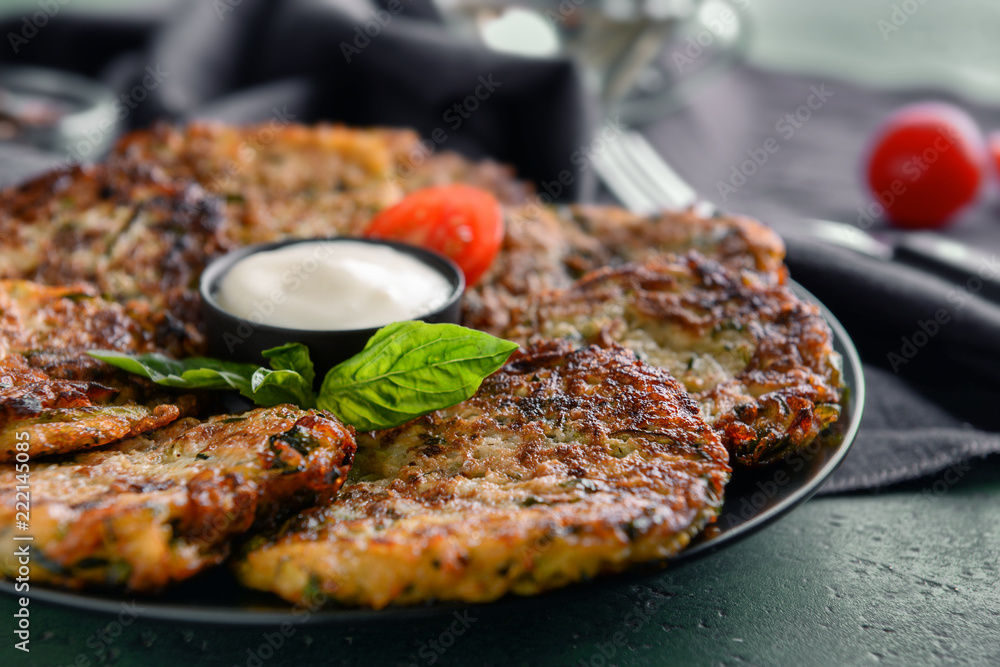 Plate with tasty zucchini pancakes on table, closeup