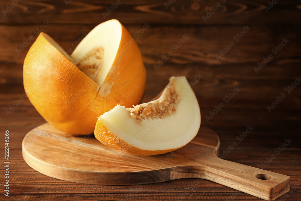 Board with ripe sliced melon on wooden table